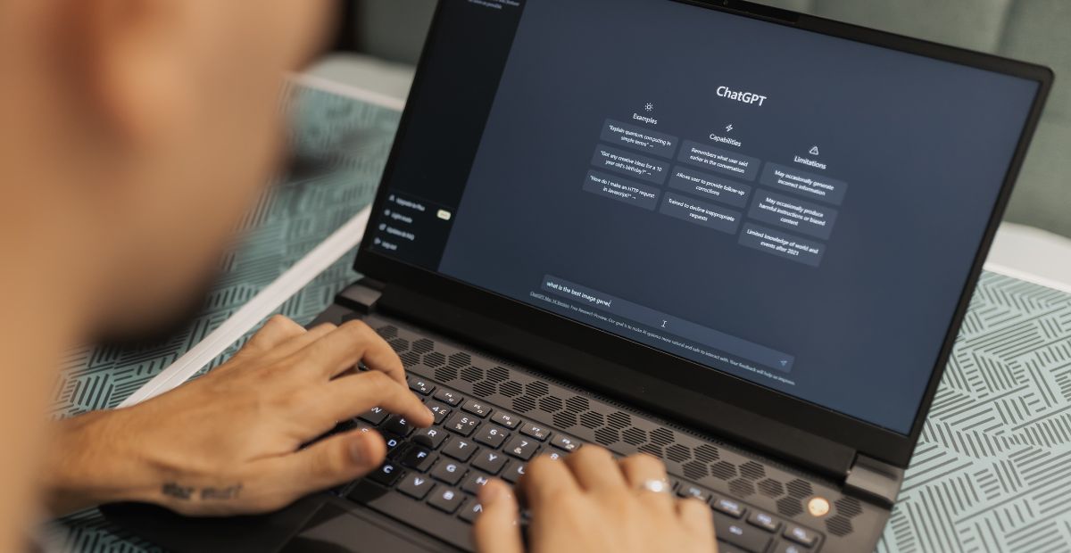 Fingers of a man using ChatGPT on his laptop trying to use chatgpt for business