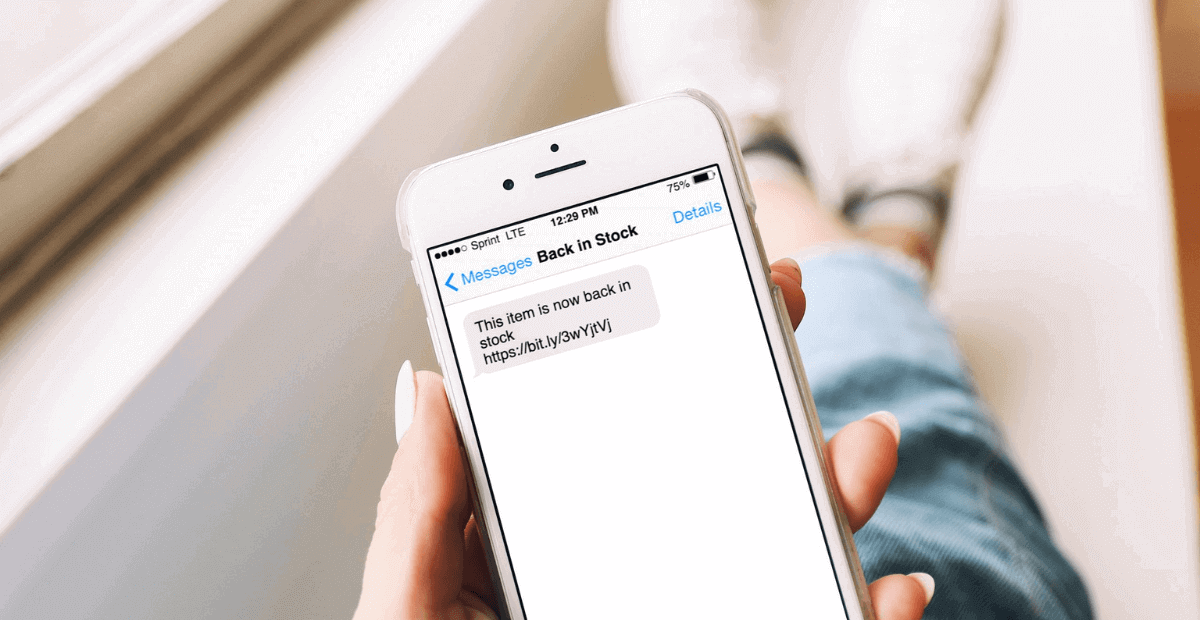 smscountry ecommerce plugin | A girl holding a mobile phone in her hand and back in stock text message opened on the screen.